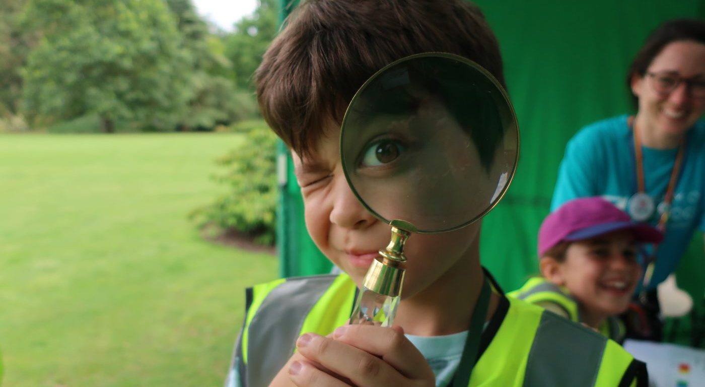 Boy looking through magnifyglass at camera