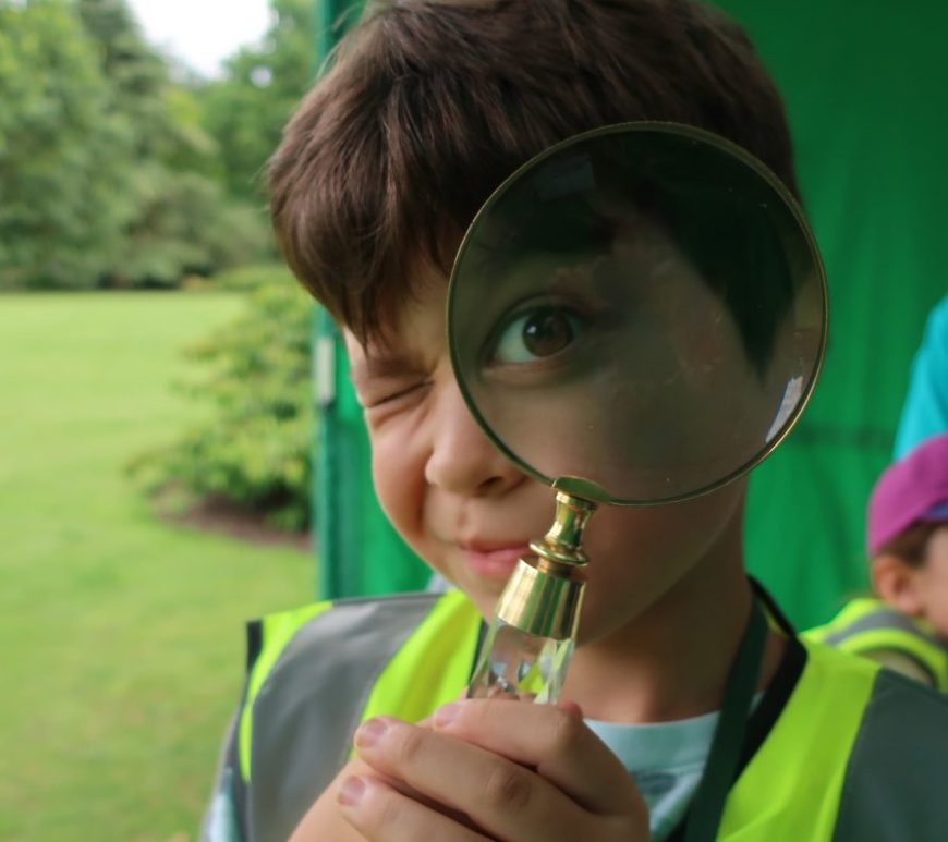 Boy looking through magnifyglass at camera