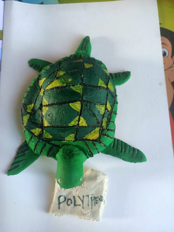 Salt dough sculpture or a green turtle with a bag in its mouth. The bag has 'polythene' written on it