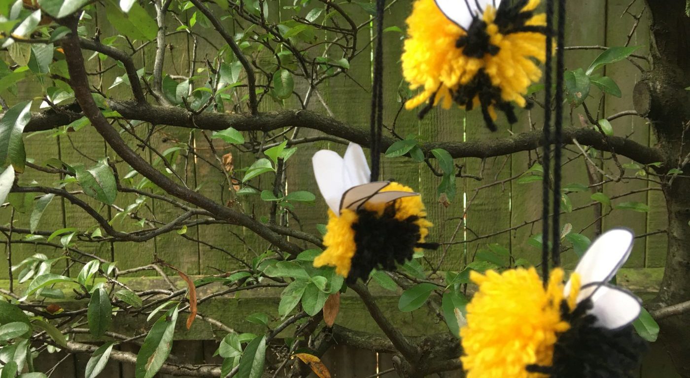 Yellow and black pom poms hanging in front of tree