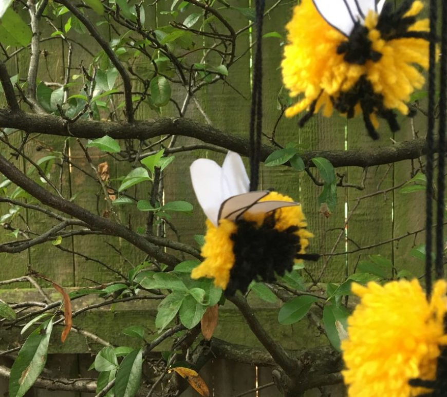 Yellow and black pom poms hanging in front of tree