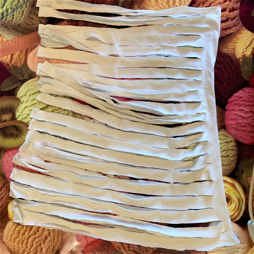 Strips cut, joined on one side, and opened out