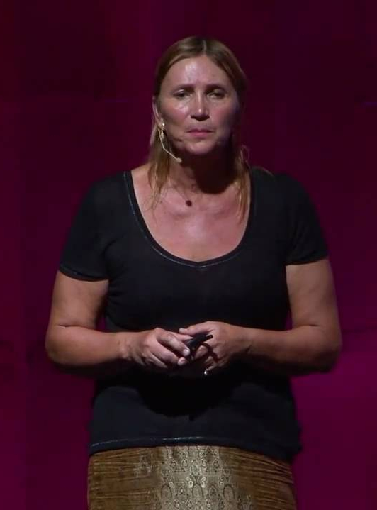 Joan Roughgarden standing in front of purple backdrop giving a lecture