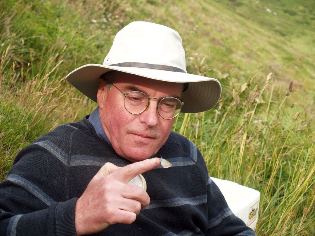 Professor Jeremy Thomas, Emeritus Professor of Ecology at the University of Oxford holds a large blue butterfly on his finger