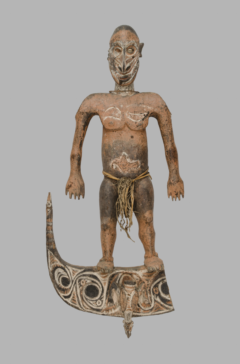 Sculpture of a man in colours of red and black with white lines and cowrie shells for eyes