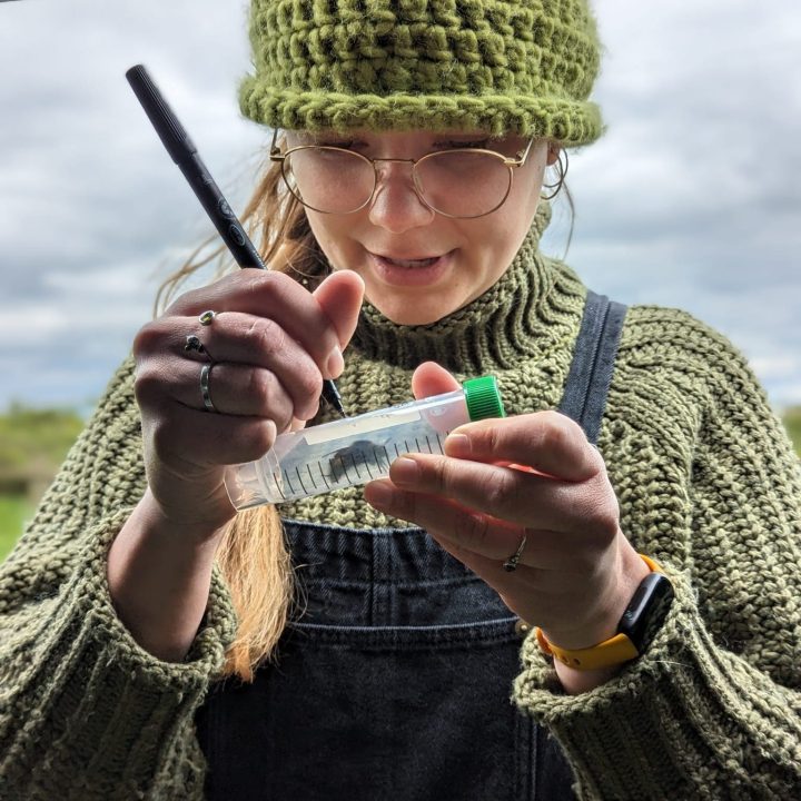 Woman in the field writing a label on a tube 
